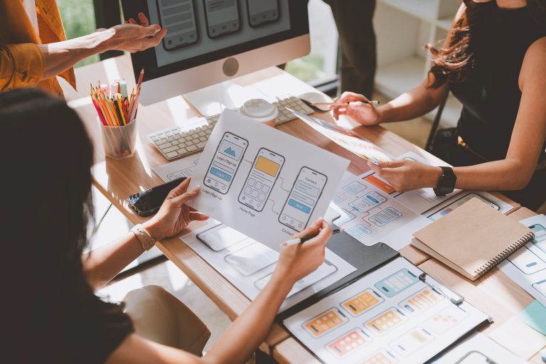 Creative team discussing and developing user interface wireframes and user experience flows for a new mobile app or software