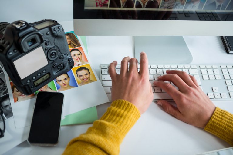 Male photographer working over computer at desk in studio