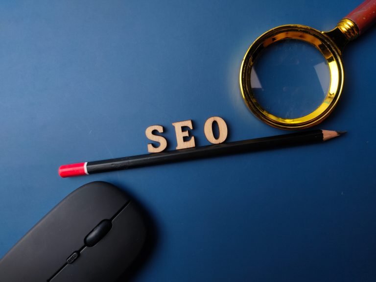 Top view pencil and word SEO with black magnifying glass on a blue background
